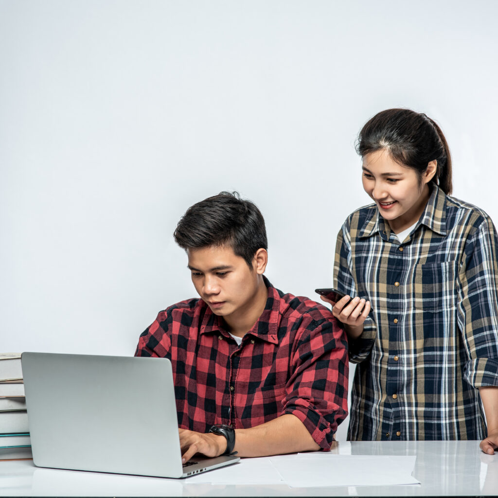 Women teach men how to work with laptops at work.